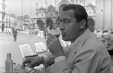 Italian actor Alberto Sordi, wearing a suit, portrayed while sipping a glass of tomato juice sitting on a terrace in St. Mark Square, salt, pepper and a lemon slice on the table in front of him, Venice, 1959. (Photo by Archivio Cameraphoto Epoche/Getty Images)