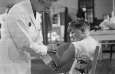 1947:  A hospitalised child suffering from polio shows off his biceps to a doctor.  (Photo by Keystone Features/Getty Images)