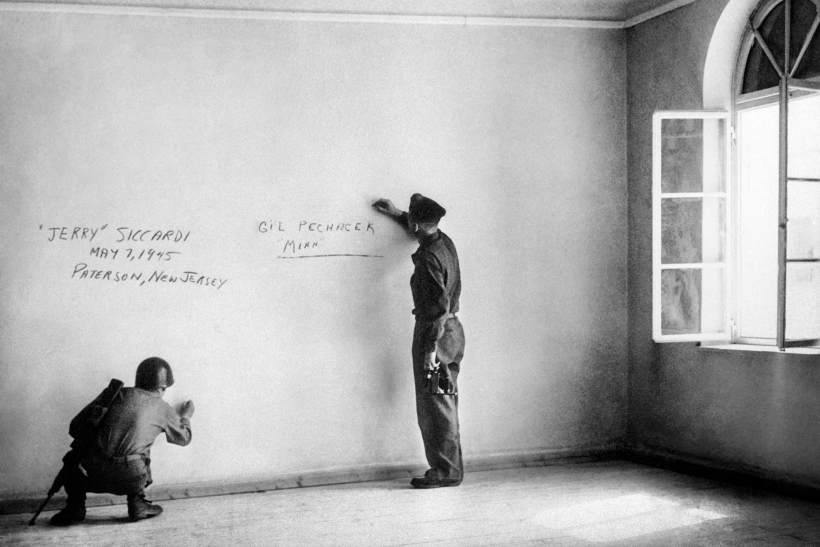 Dos soldados estadounidenses escriben grafitis sobre la pared de la habitación donde nació Adolf Hitler